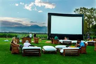Pantalla gigante en un viñedo con público listo para disfrutar cine al aire libre