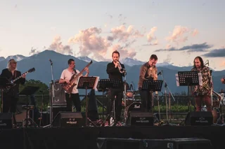 Banda de jazz tocando al aire libre entre viñedos con la cordillera al fondo