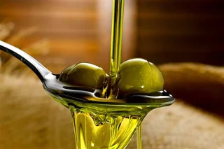 Aceite de oliva virgen vertido sobre aceitunas verdes en primer plano
